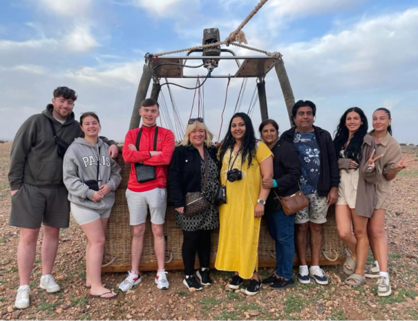 An enchanting view of the Classic Flight with Sunrise By Air Marrakech. A vibrant hot air balloon soaring gently above the golden Moroccan desert at sunrise, with panoramic views of Marrakech's stunning landscapes and distant Atlas Mountains under a colorful sky.